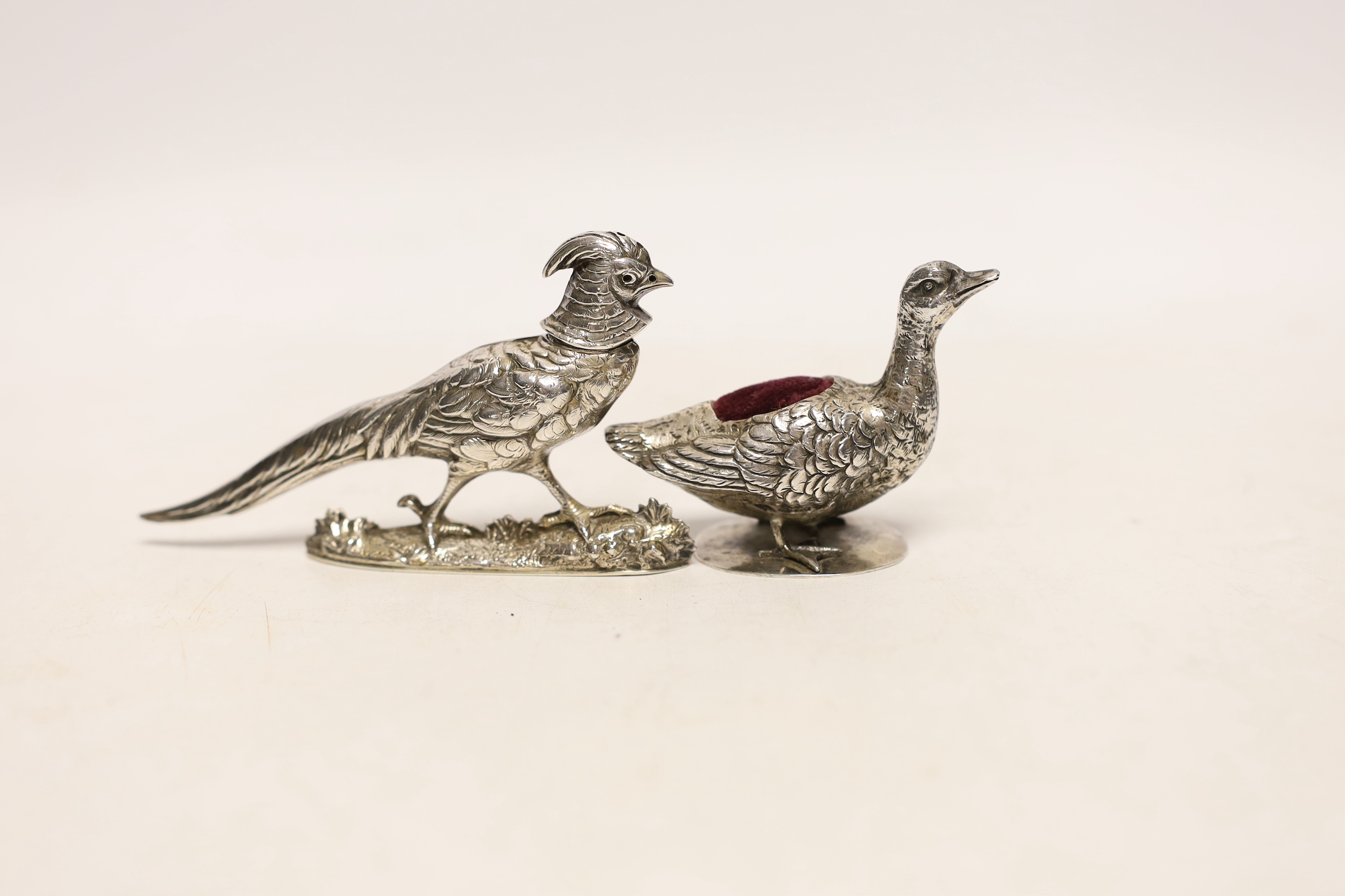 An early 20th century Hanau novelty silver pin cushion, modelled as a duck on circular base, import marks for Singleton, Benda & Co Ltd, length 64mm, together with a pepperette modelled as a pheasant, maker MF, Chester?,